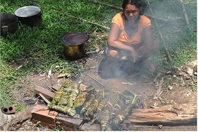 A local Shipiba, making Patarasca on the open fire. This is fish and herbs wrapped in banana leaves, tied up and then slow cooked on open coals on a grill.